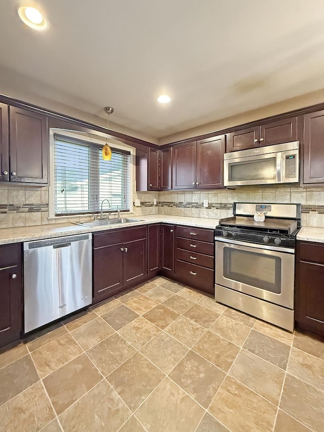 kitchen with light stone countertops, decorative light fixtures, stainless steel appliances, sink, and dark brown cabinetry