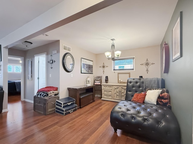 living area featuring a wealth of natural light, a chandelier, and wood-type flooring