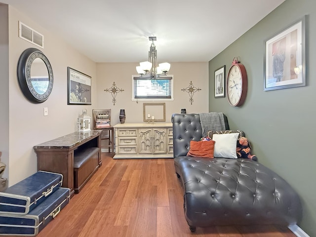 living area with an inviting chandelier and light hardwood / wood-style flooring