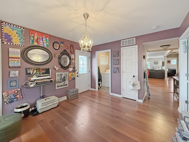 misc room with hardwood / wood-style floors, washer / clothes dryer, and an inviting chandelier