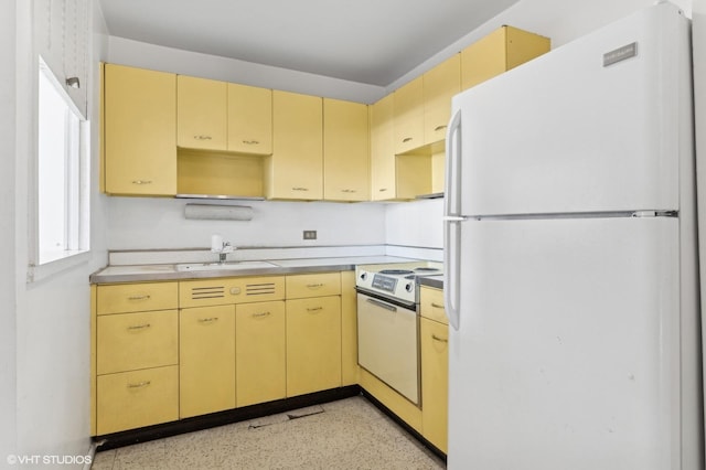 kitchen with white appliances, light brown cabinetry, and sink