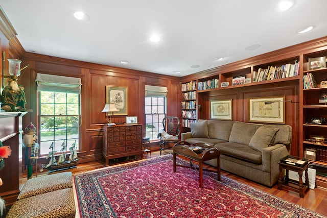 interior space with built in shelves, ornamental molding, wood finished floors, recessed lighting, and a fireplace