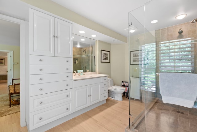 bathroom with wood finished floors, toilet, a stall shower, and vanity