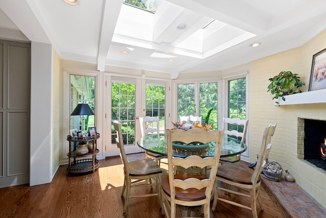 sunroom / solarium with a wealth of natural light, beam ceiling, a brick fireplace, and a skylight