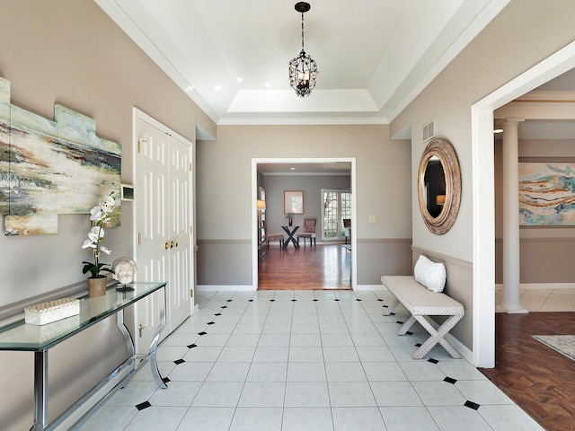 entrance foyer with light tile patterned floors, baseboards, visible vents, a tray ceiling, and ornamental molding