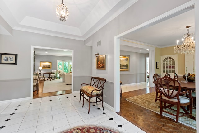 foyer entrance featuring a tray ceiling, visible vents, baseboards, and a chandelier