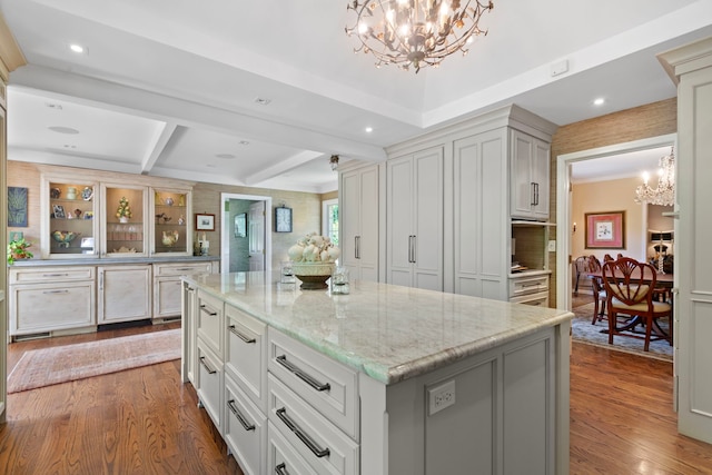 kitchen with light stone counters, dark wood-type flooring, a notable chandelier, and a kitchen island