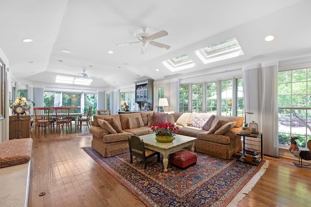 living area with vaulted ceiling with skylight, recessed lighting, a healthy amount of sunlight, and wood-type flooring