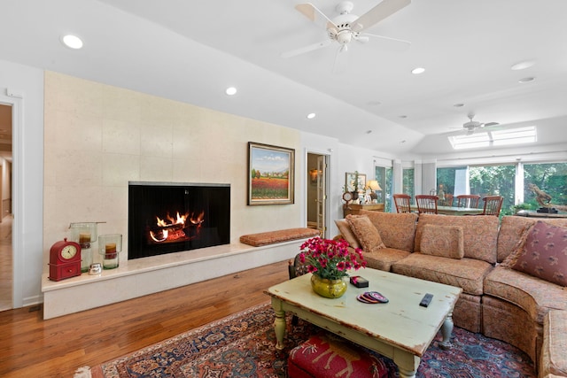 living room featuring lofted ceiling, recessed lighting, a fireplace, wood finished floors, and a ceiling fan