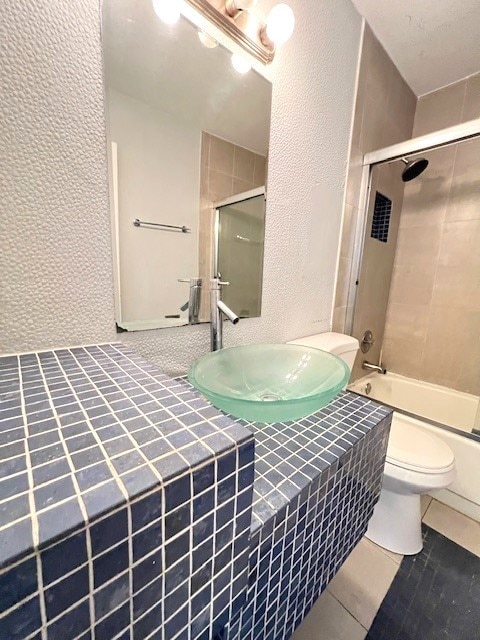 full bathroom featuring sink, toilet, tile patterned flooring, and bath / shower combo with glass door