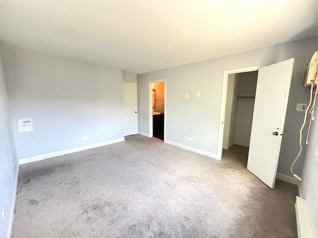 unfurnished bedroom with ensuite bathroom, carpet floors, and a closet