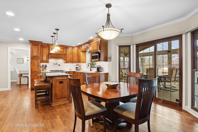 dining area featuring wood-type flooring, sink, and ornamental molding