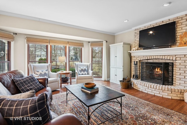 living room featuring a brick fireplace, crown molding, and hardwood / wood-style floors