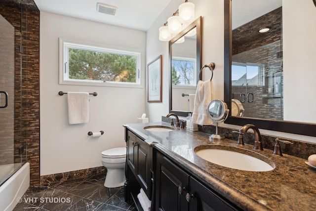 full bathroom with vanity, bath / shower combo with glass door, and toilet