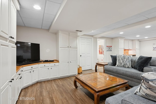 living room featuring a paneled ceiling and light hardwood / wood-style flooring