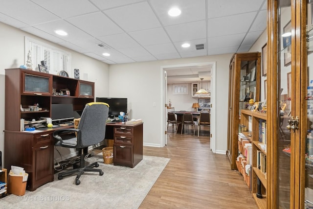 office area featuring a drop ceiling and light hardwood / wood-style flooring