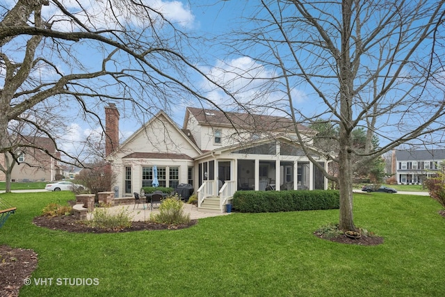 rear view of house with a patio, a sunroom, and a lawn