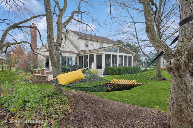 rear view of property featuring a sunroom and a lawn