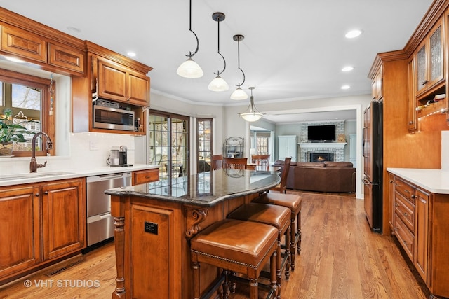 kitchen with a kitchen bar, sink, a center island, hanging light fixtures, and appliances with stainless steel finishes