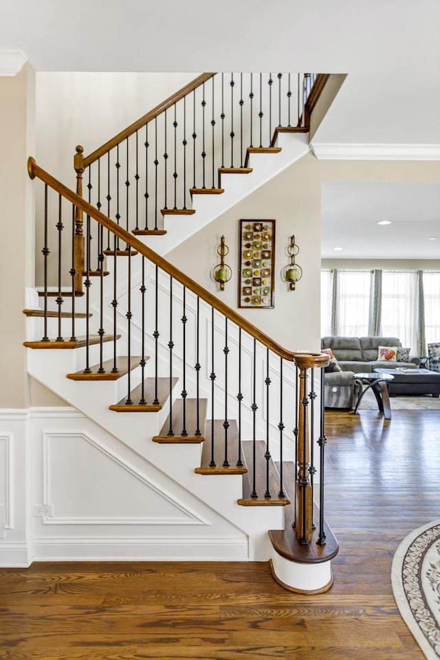 stairway with ornamental molding and wood-type flooring