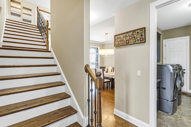 stairs featuring ornamental molding, an inviting chandelier, hardwood / wood-style floors, and washing machine and clothes dryer