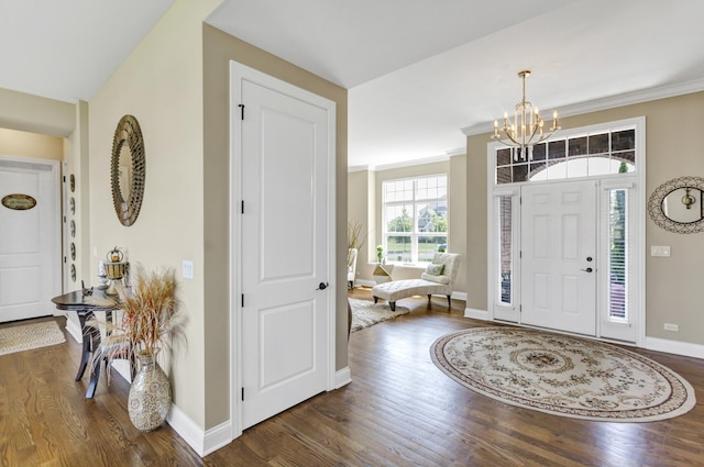 entrance foyer with dark hardwood / wood-style flooring, an inviting chandelier, and ornamental molding