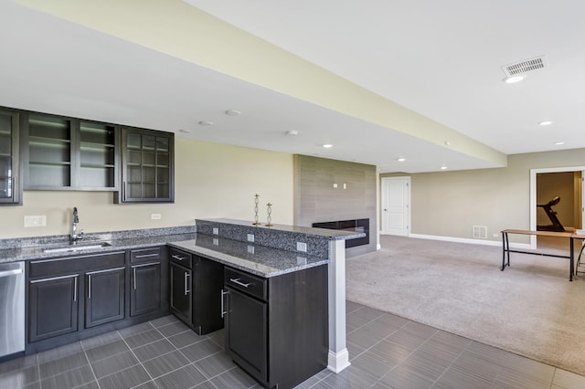 kitchen with sink, a fireplace, dishwasher, dark stone countertops, and dark carpet