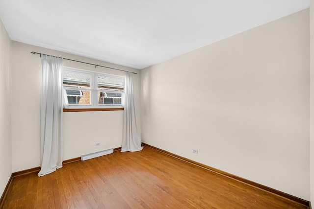 empty room with a baseboard radiator, baseboards, and light wood-style floors