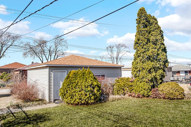 view of home's exterior featuring a yard, an outbuilding, a shingled roof, and fence