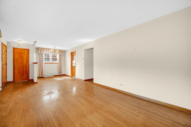 unfurnished room with a chandelier, light wood finished floors, baseboards, and a baseboard radiator