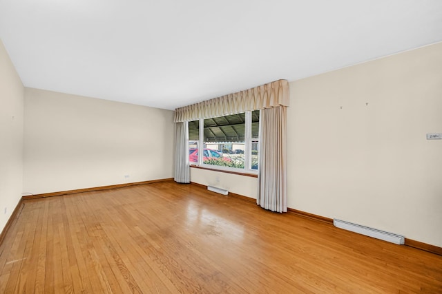 empty room featuring light wood-type flooring, a baseboard radiator, and baseboards