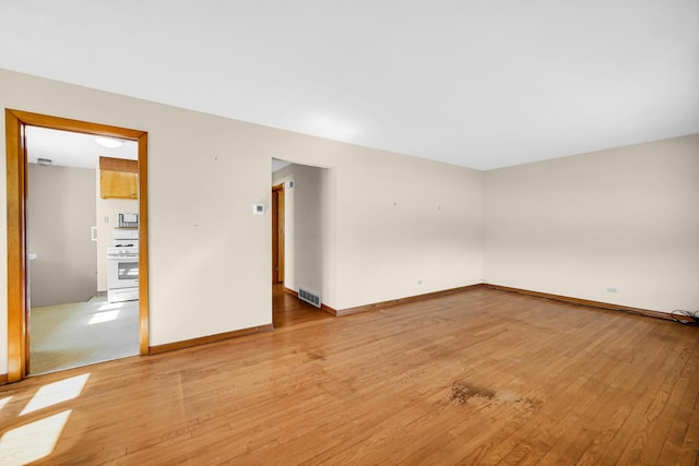 spare room with baseboards, visible vents, and light wood finished floors