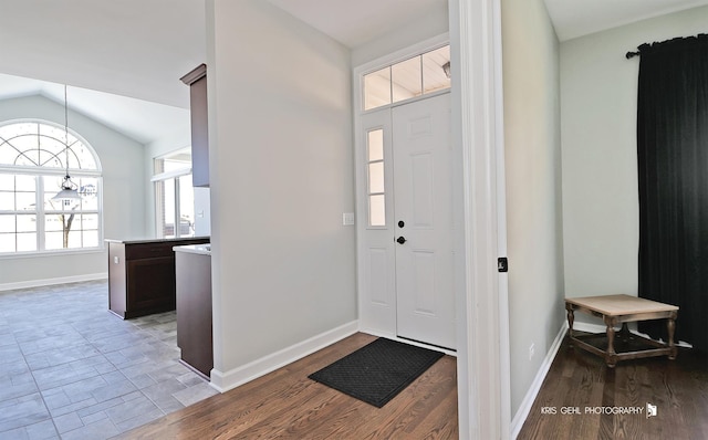 foyer with light wood-type flooring and vaulted ceiling