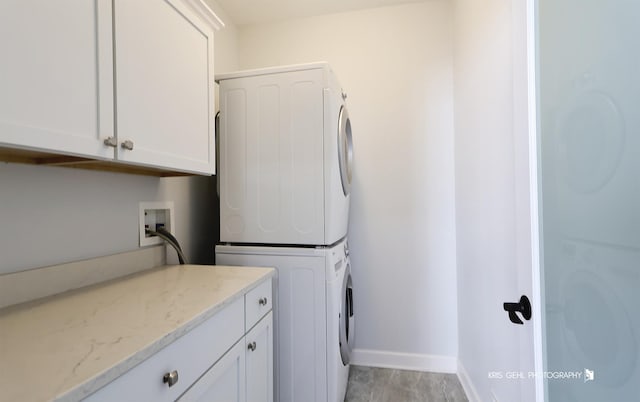 laundry room featuring cabinets and stacked washer / dryer