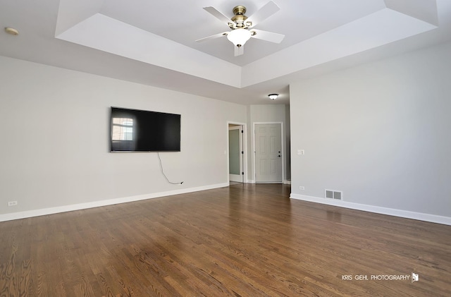 spare room with ceiling fan, dark wood-type flooring, and a tray ceiling