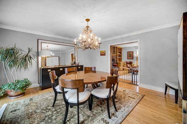 dining area featuring crown molding, an inviting chandelier, and light hardwood / wood-style floors