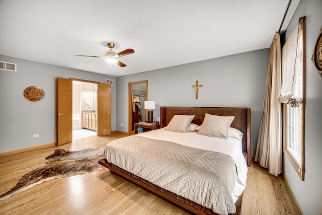 bedroom featuring ceiling fan, ensuite bathroom, and light wood-type flooring