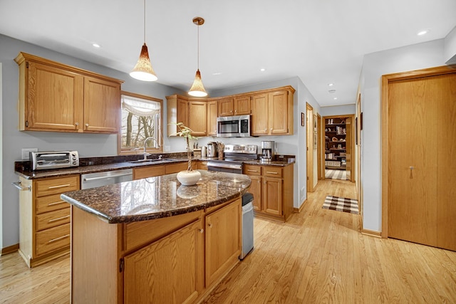 kitchen featuring sink, a center island, light wood-type flooring, appliances with stainless steel finishes, and pendant lighting