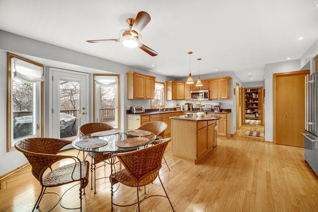 dining space with ceiling fan, sink, and light wood-type flooring