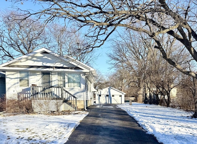 view of snow covered exterior featuring a garage and an outdoor structure