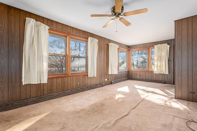 carpeted empty room featuring a baseboard heating unit and wooden walls