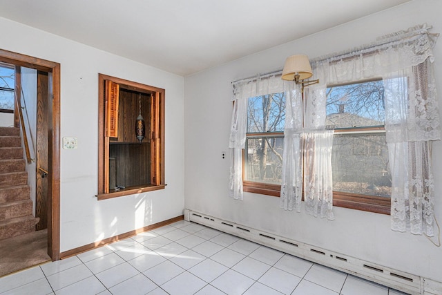 tiled empty room featuring baseboard heating