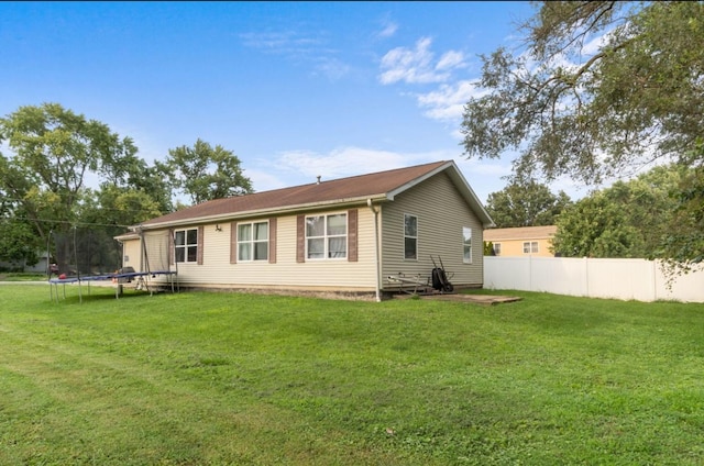 back of house with a yard and a trampoline