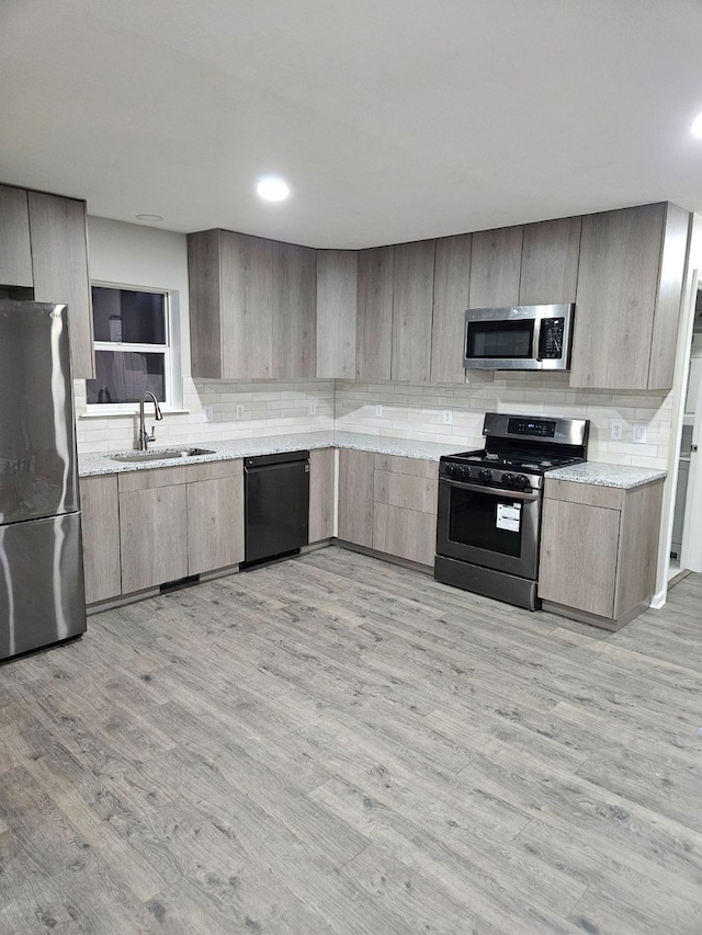 kitchen with stainless steel appliances, light hardwood / wood-style floors, backsplash, and sink