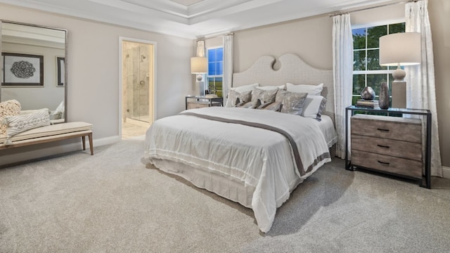 carpeted bedroom with ensuite bath, a raised ceiling, and ornamental molding