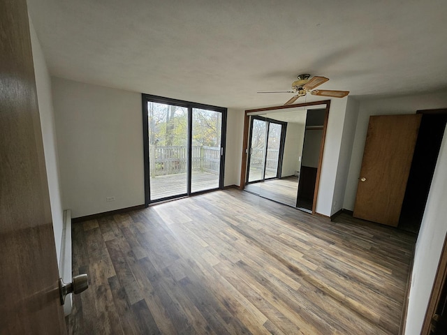 unfurnished room with ceiling fan, expansive windows, and hardwood / wood-style floors