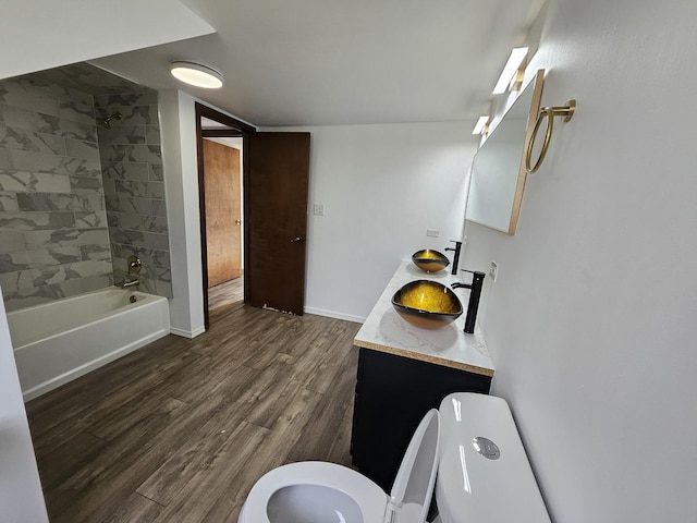 full bathroom featuring wood-type flooring, toilet, tiled shower / bath, and vanity