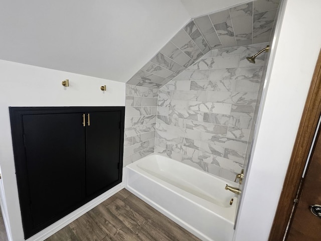 bathroom featuring hardwood / wood-style floors, tiled shower / bath combo, and lofted ceiling