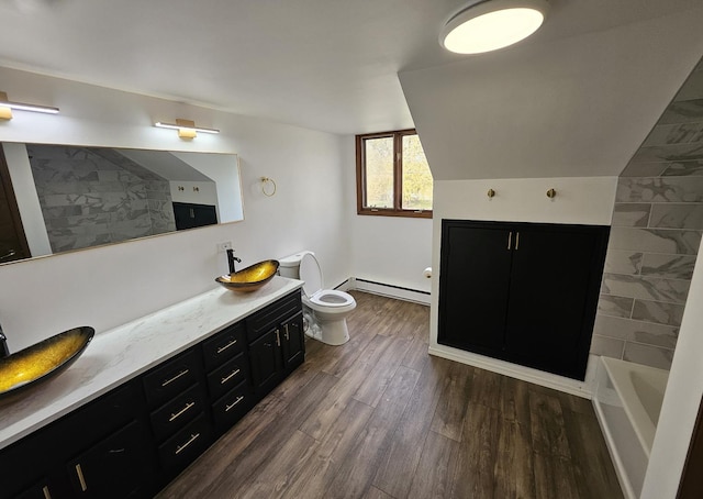 bathroom featuring wood-type flooring, a baseboard radiator, vaulted ceiling, toilet, and vanity