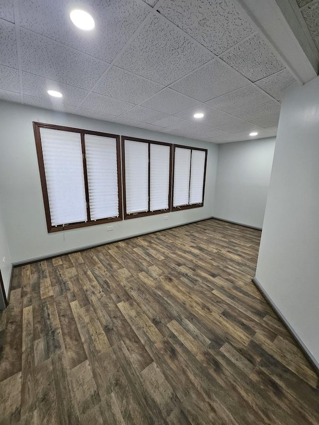 basement featuring dark hardwood / wood-style flooring and a drop ceiling